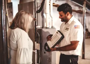 A Boulden Brothers technician discussing furnace repair options with a homeowner in front of a heating system.